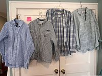 Four plaid button-up shirts hanging