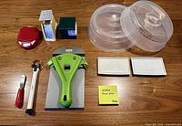 All items laid out on table: scale, timer, cube gadget, Kuhn Rikon opener, jar opener, spreader, microwave covers, trays