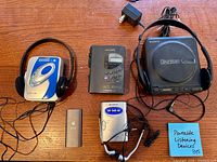 Five portable audio devices laid out: Sony Discman with AC adapter, Craig CD player with headphones, Koss cassette player, Apple iPod Nano, Sony Walkman radio with earbuds
