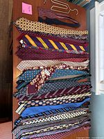All neckties arranged flat on tabletop showing colors, patterns and included hanger