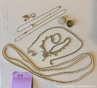 Overview of all ten jewelry pieces laid on surface including necklaces, earrings, ring and brooch