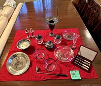 All serving pieces arranged on red cloth showing quantity and condition