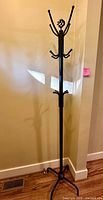 Full view of black metal coat rack showing hooks and base
