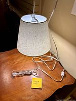 Lamp with beige fabric shade, cord, plug and inline switch visible on table