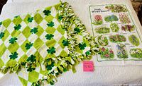 Throw blanket folded showing pattern and fringe next to unfolded tea towel with floral print