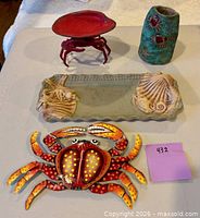 Overview of four nautical/coastal décor pieces: metal crab wall art, metal crab dish, ceramic seashell tray, turquoise ceramic holder