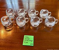 Front view of eight Nestle glass world map mugs aligned on table