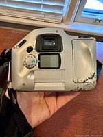 Rear/top view of Nikon SLR showing mode dial, LCD, strap, paint chipping