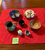 All seven ceramic pieces arranged on red cloth