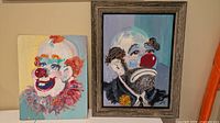 Both clown portrait paintings side by side showing size and framing