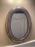 Front view of oval antique silver metal wall mirror