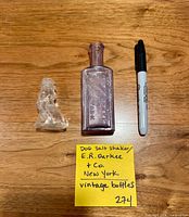 Bottle, dog shaker and marker for scale with note card