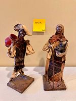 Front view of both paper mâché figurines showing size, pose, colors and wear