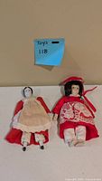 Both porcelain head dolls on table showing size, outfits and condition