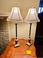 Front view of both tall gold and cream table lamps on wooden surface