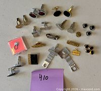Group shot of assorted cufflinks, studs, tie bars and charm on tabletop