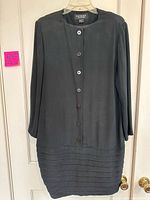 Front of black silk dress hanging to show style, buttons, pleated lower section