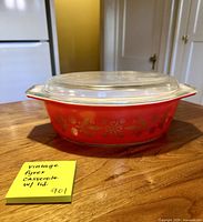 Side view of red Pyrex casserole with gold floral decal and clear lid