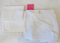 Full view of queen flat sheet and two pillowcases with embroidered eyelet pattern, tag visible