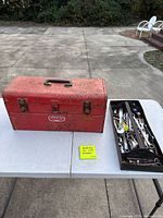 Red Proto toolbox and tray of assorted hand tools displayed on table