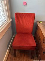 Front view of red upholstered dining chair with wooden legs