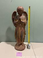 Full view of angel statue beside tape measure showing height