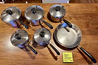 Top view showing six pans and five lids arranged on table