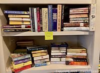 Two shelves filled with stacked and shelved paperback romance and women’s fiction books