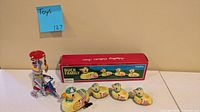 Group shot showing Duck Family tin toys, original box, clown tricycle toy and key