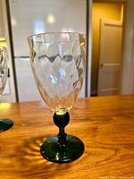 Single goblet close-up showing faceted clear bowl and green stem/base
