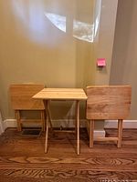 Three natural wood folding tray tables, one opened and two folded