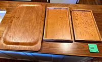 Three wooden trays on countertop, showing sizes and handles