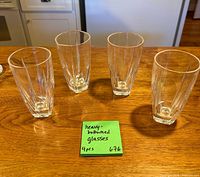 Four clear faceted tall glasses on wooden surface