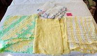 Four crocheted baby blankets folded on a bed showing color and pattern variety