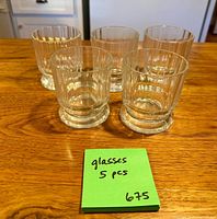 Five clear ribbed glass tumblers grouped on wooden surface