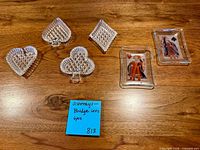 All six pressed glass ashtrays displayed on wood surface showing lattice designs and playing card inserts