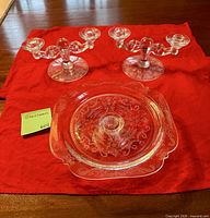 Two candle holders and three-piece serving dish displayed on red cloth