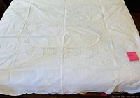 Large white lace tablecloth spread showing oval and circular cut-work pattern
