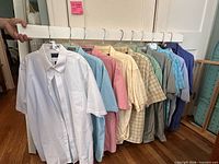 Twelve assorted short-sleeve button-up shirts hanging on rack