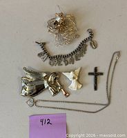 Overview of six religious jewelry pieces laid out: brooch, bracelet, two angel pendants, cross pendant, necklace