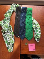 Scarf, three shamrock neckties and lapel pin laid out on wooden surface