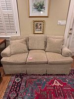 Front view of beige three-seat sofa with cushions and throw pillows