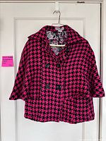 Front view of Steve Madden pink and black houndstooth coat on hanger