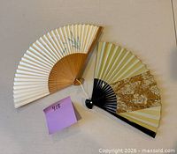 Both folding hand fans fully opened showing paper leaves, motifs and wooden guards