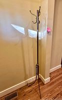 Full view of disassembled traditional style metal coat rack with hooks and legs