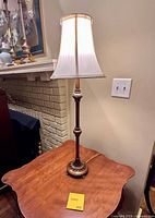 Full view of brass table lamp with shade on wooden table