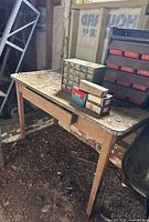 Wooden workbench with drawer topped by metal and plastic parts organizers and hardware boxes