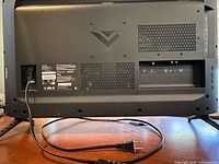 Rear view of Vizio TV showing ports, ventilation, logo and attached feet, power cord visible
