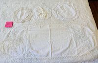 Top-down view showing oval lace tablecloth and three round lace doilies laid out on surface