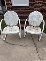 Front view of both white metal patio chairs showing mildew and paint loss